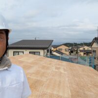 屋根の上で小椋孝一が現場を確認している様子