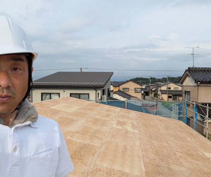屋根の上で小椋孝一が現場を確認している様子
