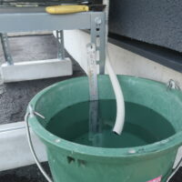 エアコン室外機のドレン排水管を14Lバケツに入れて除湿量を測る様子