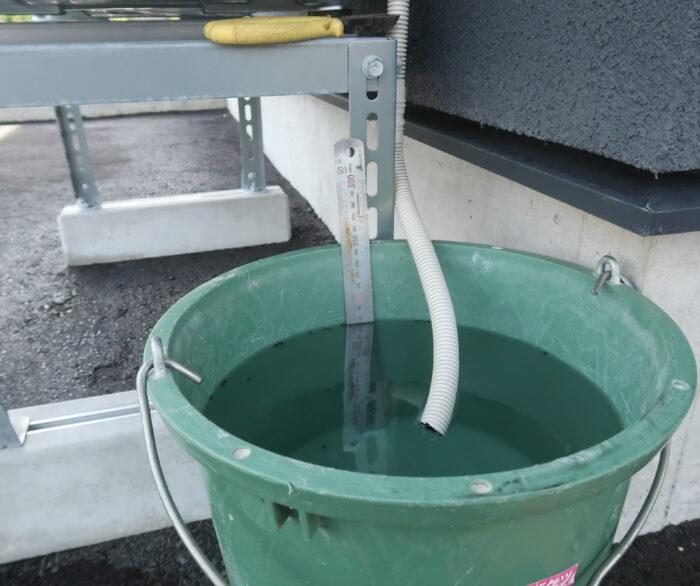 エアコン室外機のドレン排水管を14Lバケツに入れて除湿量を測る様子